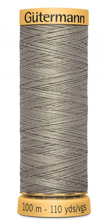 Spool of Gütermann thread with gray thread on a white background