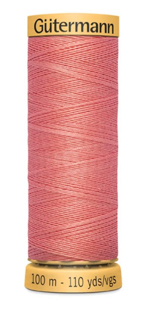 Spool of Gütermann pink thread on a white background