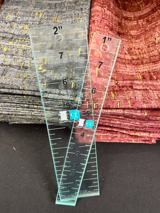 Two clear plastic rulers with measurements on a textured surface