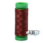 Spool of red thread with green end on a white background