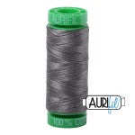 Spool of gray thread with green end cap on a white background