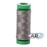 Spool of gray thread with a green top on a white background
