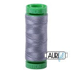 Spool of gray thread with green end, brand 'Aurifil' visible