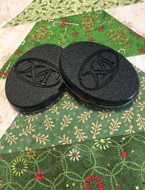 Two black round objects with a logo on a green patterned fabric background