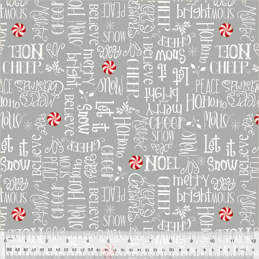 Christmas-themed fabric with holiday phrases and candy cane designs on a gray background, measured with a ruler.