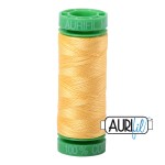 Spool of yellow thread with green top on a white background