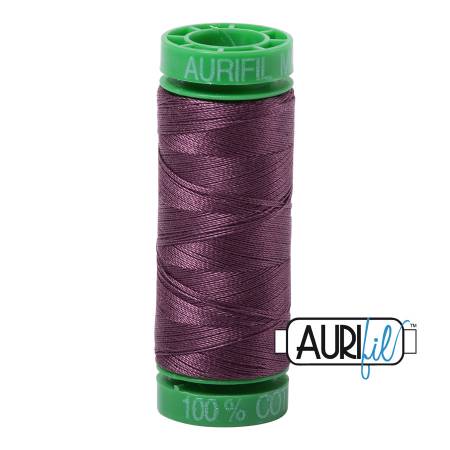 Spool of Aurifil thread with a purple thread on a white background