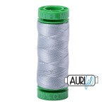 Spool of gray thread with green cap on a white background