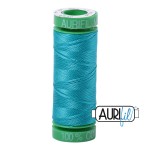 Spool of blue thread with green top on a white background