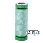 Green spool of thread with 'Aurifil' branding on a white background