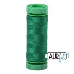 Spool of green thread with 'AURUM' branding on a white background