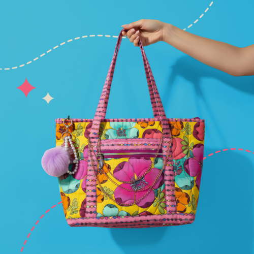 Colorful floral-patterned handbag with pink handle against a blue background