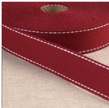 Close-up of red ribbon with white stitching on a textured beige background