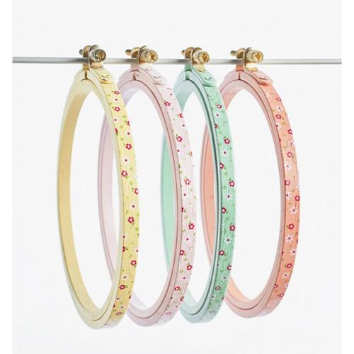 Set of four pastel-colored embroidery hoops with floral patterns on a white background
