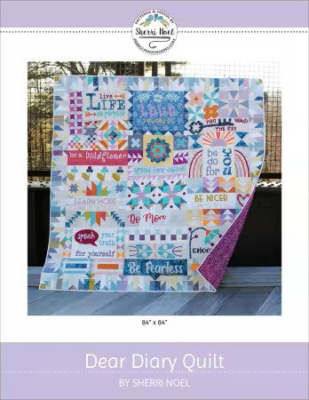 Colorful quilt with motivational phrases on a white background, featuring the brand 'Sherri Noel'.