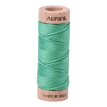 Spool of teal thread on a wooden reel with 'Aurifil' branding on a white background