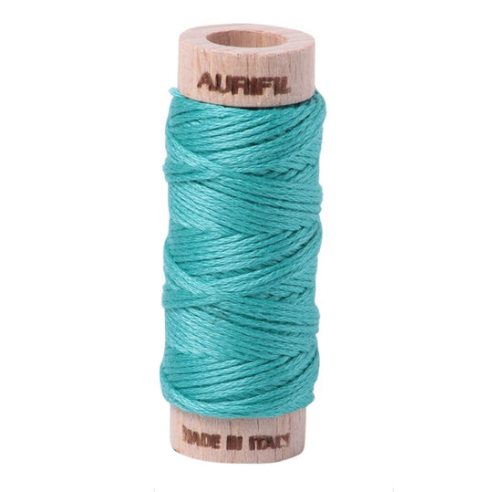 Spool of teal thread on a white background with 'Aurifil' branding.