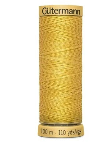 Spool of yellow Gutermann thread on a white background