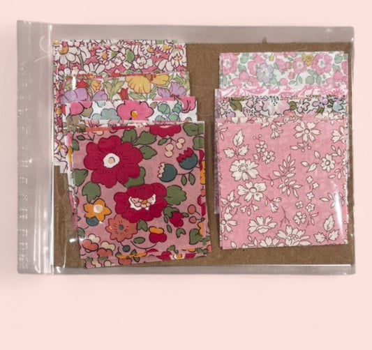 Set of floral-patterned paper sheets in a clear plastic packaging on a beige background