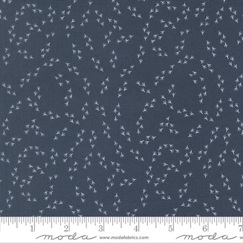 Fabric with small white floral pattern on a blue background, featuring Moda label.
