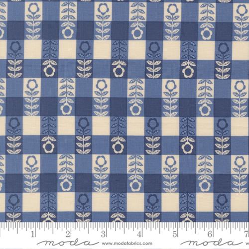 Fabric pattern with blue and beige checkered design featuring floral elements, branded 'Moda'.