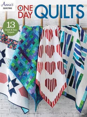 Book cover of 'One Day Quilts' with colorful quilts on a wooden rack.