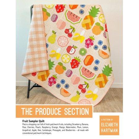 Colorful quilt with fruit patterns on a chair, featuring the text 'The Produce Section' by Elizabeth Hartman.