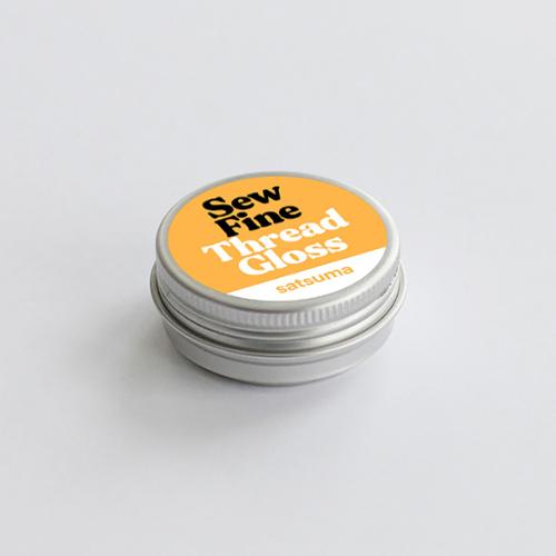 Sew Fine Thread Gloss container with yellow label on a light gray background