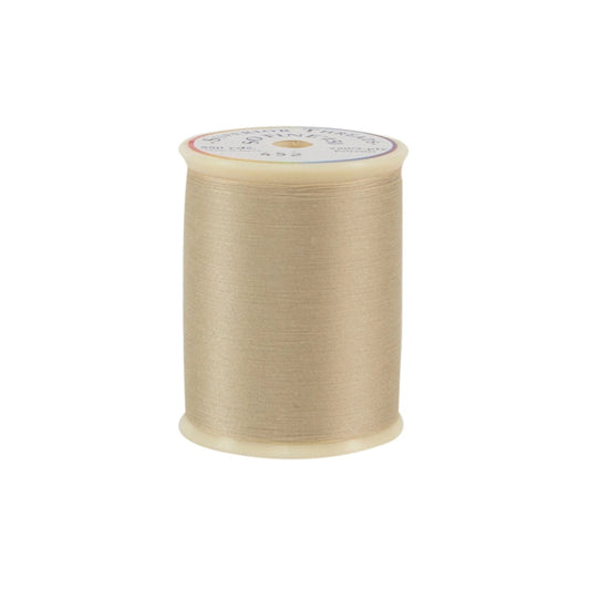 Spool of beige thread on a white background