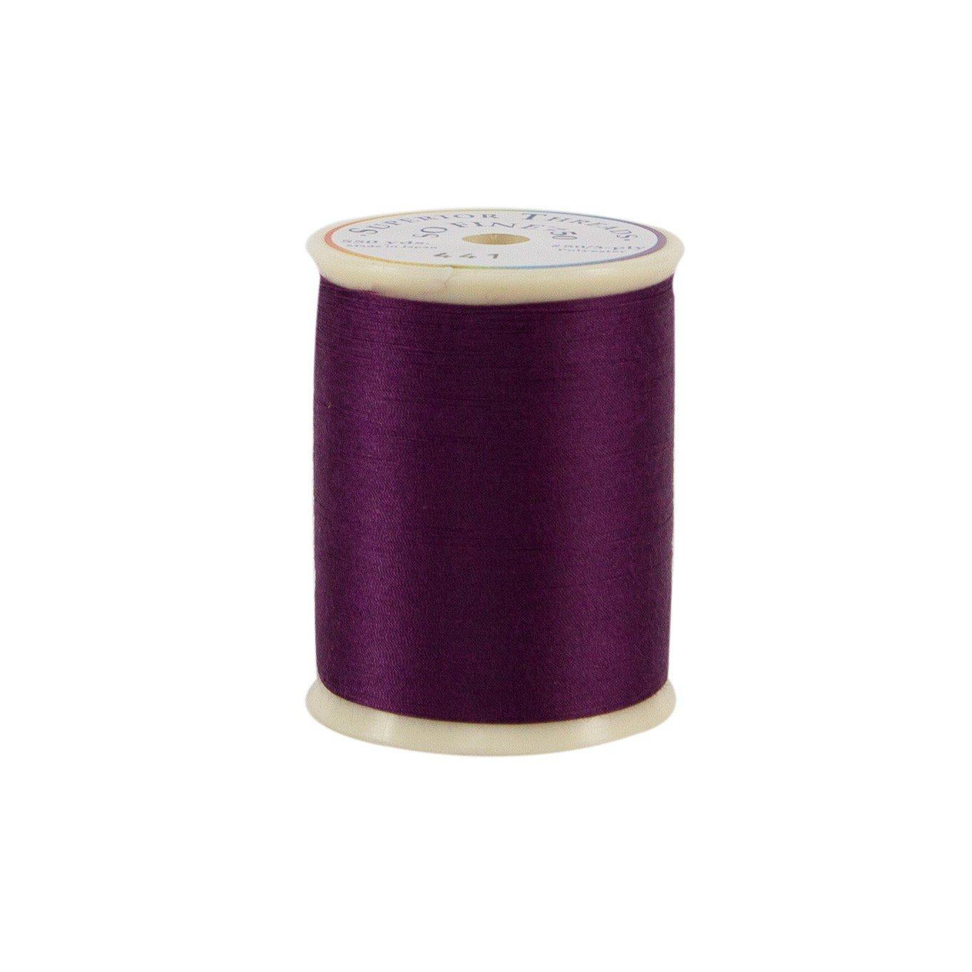 Spool of purple thread on a white background