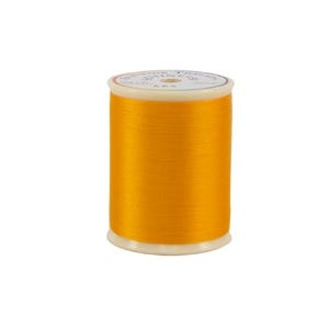 Spool of yellow thread on a white background