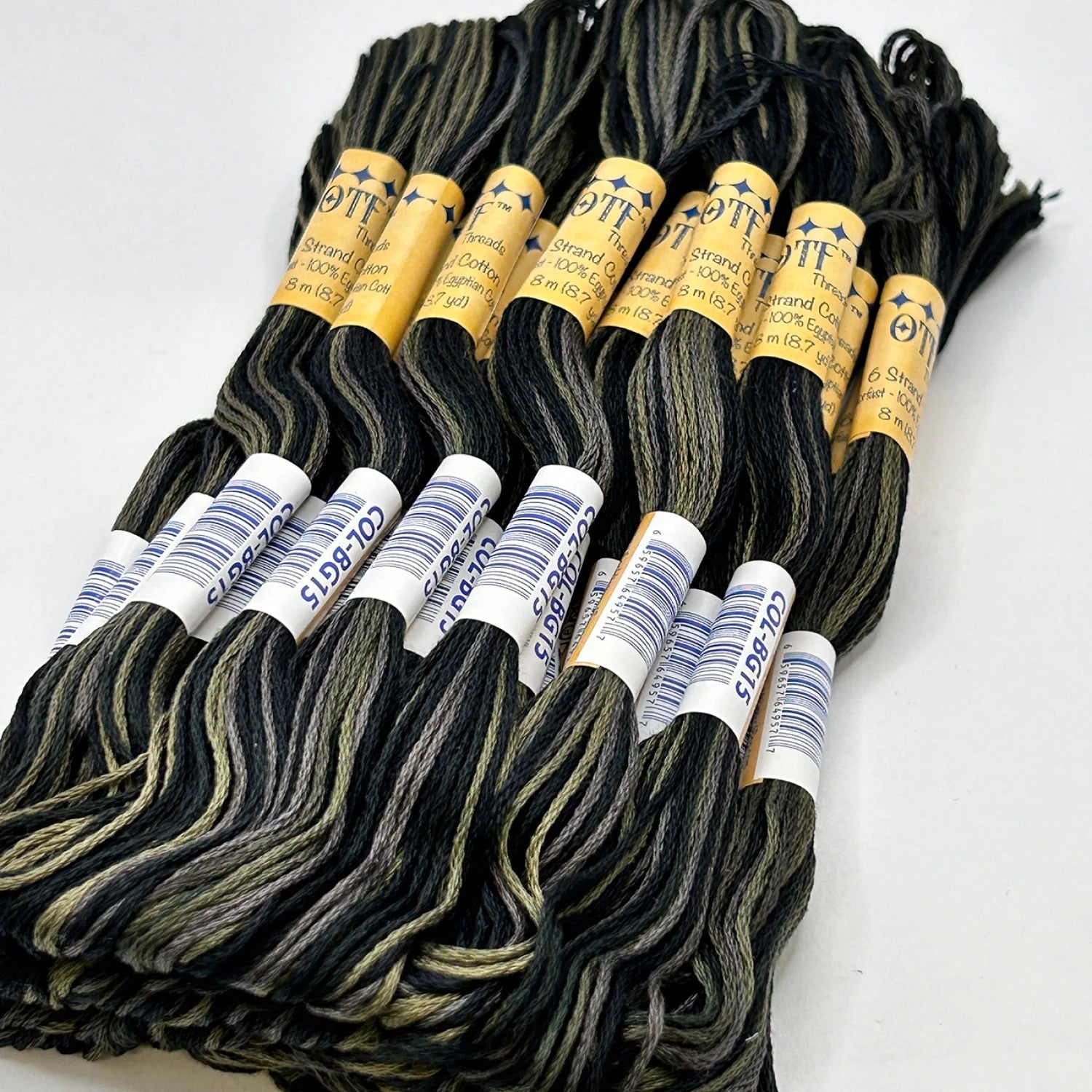 Bundles of black and gold embroidery floss with labeled ends on a white background