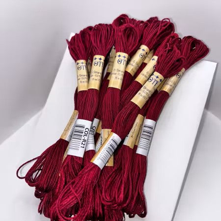 Red embroidery floss with labels on a white surface
