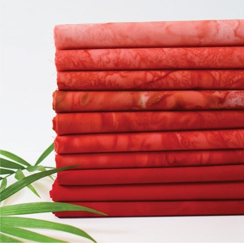 Stack of red fabric rolls with green leaves on a white background